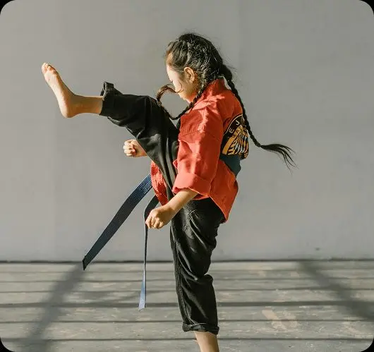 Young female martial artist mid-kick, representing student athletes and performers who balance training with Teneo Online School studies