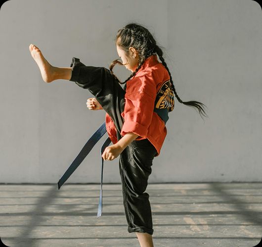 Young female martial artist mid-kick, representing student athletes and performers who balance training with Teneo Online School studies